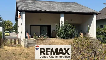 Einfaches Einfamilienhaus mit Vordach und Gartenbereich in sonniger Lage.