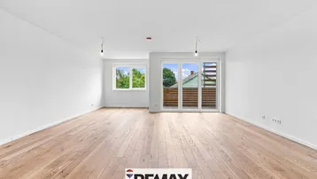 Helles, leeres Wohnzimmer mit modernem Holzparkett und Zugang zu einem Balkon oder einer Terrasse.