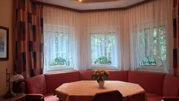 Gemütlicher Essbereich mit Eckbank, vielen Fenstern und einer Holzdecke mit integrierter Beleuchtung.