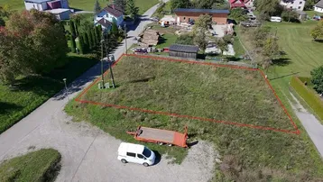Luftaufnahme eines Baugrundstücks mit roter Umrandung und umliegender ländlicher Bebauung.