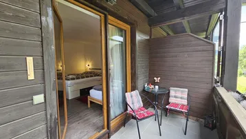 Gemütlicher Balkon mit Sitzgelegenheiten und Blick in ein helles Schlafzimmer.