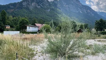 Weitläufiges Grundstück mit Blick auf die umliegende Berglandschaft unter bewölktem Himmel.