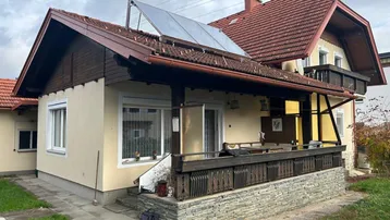 Traditionelles Haus mit Satteldach, Holzbalkon und Solarpaneelen auf dem Dach.