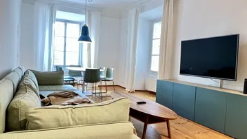 Helles Wohn- und Esszimmer mit Holzdielenboden, bequemer Couch und modernem Esstisch.
