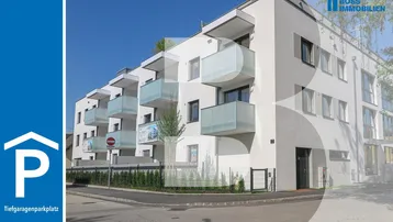 Modernes Mehrfamilienhaus mit weißer Fassade, großen Fenstern und mehreren Balkonen.