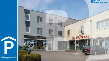Gebäudeansicht mit Geschäften, Parkplätzen und Hinweis auf Tiefgaragenstellplätze.