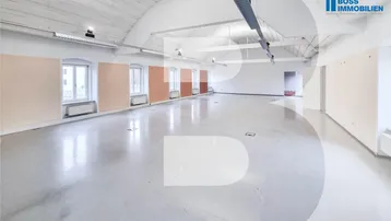 Großer, leerer Büroraum mit hohen Gewölbedecken, hellen Wänden und glänzendem Betonboden.