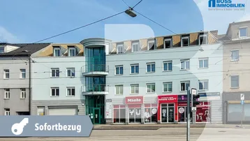 Fassade eines modernen Geschäfts- und Bürogebäudes mit großen Fenstern und einem markanten runden Eingangsbereich.