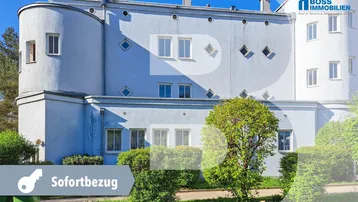 Außenansicht eines hellblauen Gebäudes mit markanten runden Formen und verschiedenen Fensterdesigns.