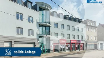 Fassade eines Mehrzweckgebäudes mit Geschäften im Erdgeschoss und Wohnungen darüber, teilweise durch Overlay verdeckt.