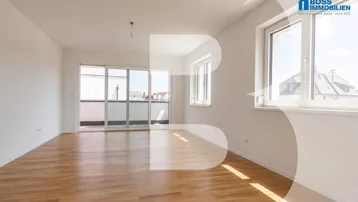 Heller, unmöblierter Raum mit hellem Holzfußboden, weißen Wänden und Zugang zu einem Balkon.