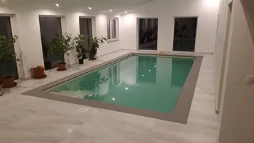 Heller Innenpoolbereich mit großen Fenstern und Fliesenboden, ideal zur Entspannung und Fitness.