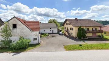 Ansicht von mehreren Gebäuden und einem großen gepflasterten Hof unter blauem Himmel mit Wolken.