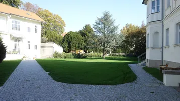 Großer, gepflegter Innenhof mit Rasenfläche und gepflasterten Wegen zwischen den Gebäuden.