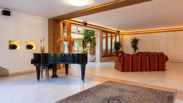 Geräumiger Wohnbereich mit Klavier, gemütlichen Sofas und hellem Fliesenboden.