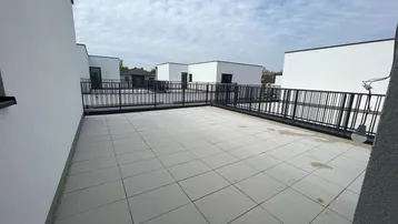 Geräumige Dachterrasse mit modernen Fliesen und Blick auf die umliegenden Neubauten.