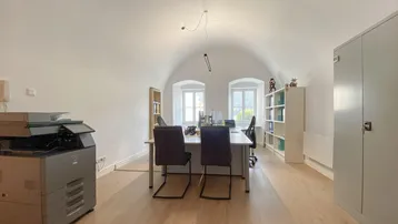 Geräumiges Büro mit Gewölbedecke, zwei Fenstern, Schreibtischen und Stauraum.
