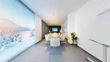 Moderner Konferenzraum mit großem Tisch, bequemen Stühlen und einer beeindruckenden Winterlandschaft als Wandbild.