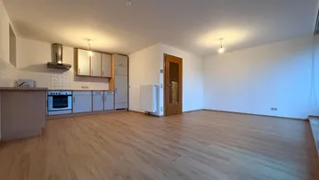 Offener Wohn- und Essbereich mit integrierter Küche und hellem Laminatboden in gutem Zustand.
