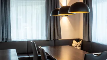 Gemütlicher Essbereich mit dunklem Holztisch, bequemer Sitzbank und modernen Pendelleuchten.