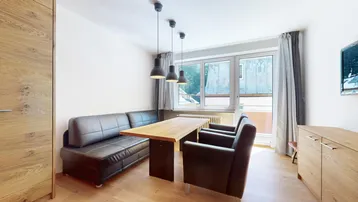 Heller Wohn- und Essbereich mit Holztisch, Ledersitzbank und Blick ins Grüne durch große Fenster.