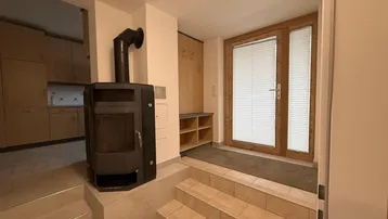Eingangsbereich mit Holzofen, Garderobe und Treppe, die zu weiteren Räumen führt.