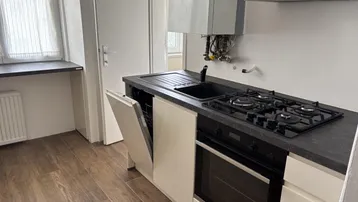 Moderne Küche mit Gasherd, Backofen, Spülmaschine und Hängeschränken, ausgestattet mit einem Boiler.