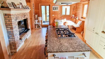 Rustikale Holzküche mit großer Kochinsel, Granitarbeitsplatte und gemauertem Kamin.