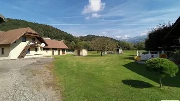 Großzügige Rasenfläche mit Blick auf die Gebäude und die umliegende Berglandschaft.