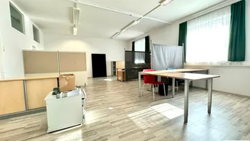 Geräumiger Büroraum mit mehreren Arbeitsplätzen, großen Fenstern und hellem Laminatboden.