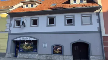 Fassade eines Gebäudes mit Geschäften im Erdgeschoss und Wohnungen darüber in einer städtischen Umgebung.