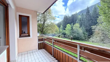 Geräumiger Balkon mit Fliesenboden und einem malerischen Blick auf die umliegende Berglandschaft und Wälder.