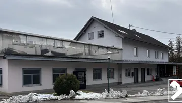 Gebäudeansicht mit einer Mischung aus traditioneller Architektur und einem modernen Glasanbau im Winter.