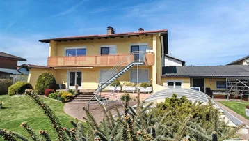 Großzügiger Gartenbereich mit Rasenfläche, überdachtem Pool und Zugang zur Terrasse.