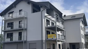 Seitenansicht des modernen Wohngebäudes mit gestaffelten Balkonen und Schrägdach.