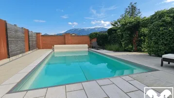 Privater Swimmingpool mit gepflasterter Sonnenterrasse und herrlichem Bergblick im Hintergrund.