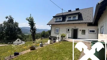 Hausfassade mit Terrasse und weitem Blick über die hügelige Landschaft und Berge.