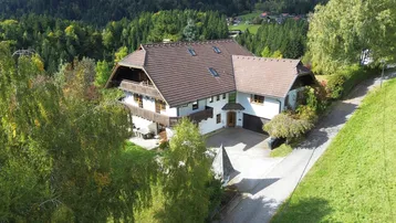 Großes Einfamilienhaus in ländlicher Umgebung mit Satteldach und umliegendem Grün.