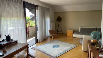 Helles Wohnzimmer mit Holzboden, gemütlicher Sitzecke und Zugang zu einem Balkon.