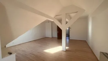 Heller Wohnbereich im Dachgeschoss mit Holzboden, Dachschräge und sichtbaren Balken.