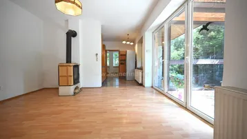 Helles Wohnzimmer mit Laminatboden, Kaminofen und großen Fenstern zum Gartenbereich.
