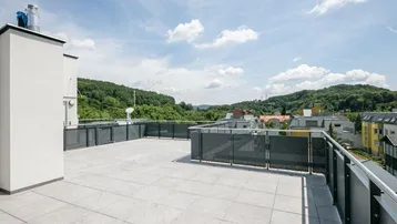 Große Dachterrasse mit Fliesenboden und weitem Blick auf die umliegende grüne Hügellandschaft.