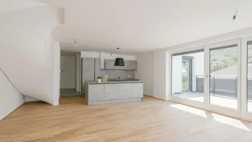 Heller, offener Wohn- und Essbereich mit moderner Küchenzeile und Zugang zur Terrasse.