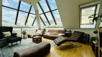 Helles Wohnzimmer mit großen Dachfenstern, Holzboden und bequemen Ledersofas.