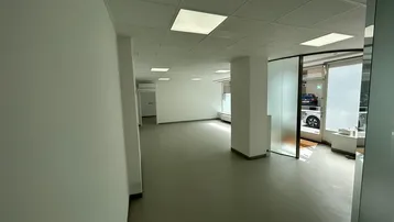 Geräumiger, heller Büroraum mit abgehängter Decke, Einbauleuchten und großen Fenstern zur Straße.