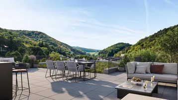 Geräumige Dachterrasse mit modernen Möbeln, Bar und weitem Blick auf die bewaldeten Hügel.