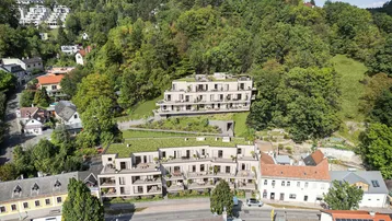 Luftaufnahme einer modernen Wohnanlage mit mehreren Gebäuden, umgeben von viel Grün und Bäumen.