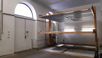 Geräumige Tiefgarage mit automatischem Parksystem und Tageslicht durch ein großes Bogenfenster.