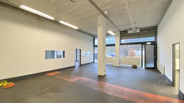 Leerer, heller Gewerberaum mit großen Fenstern und Betonboden, bereit für die individuelle Gestaltung.