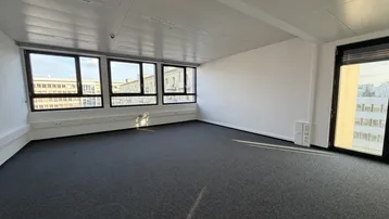 Geräumiges, leeres Büro mit großen Fenstern, die viel Tageslicht hereinlassen und einen weiten Blick bieten.